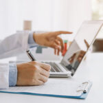 North Carolina Officials Scrutinize Hospitals Undermining Price Transparency Rules Doctor in hospital writing medical documentation and using laptop