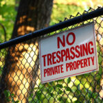 Profile: Empire Center – Working Toward A Better New York A close-up image of a 'No trespassing - private property' sign hanging on a fence with green trees on the background