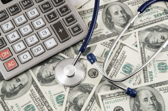 Calculator and stethoscope on banknotes background, cost of healthcare concept, conference for money management