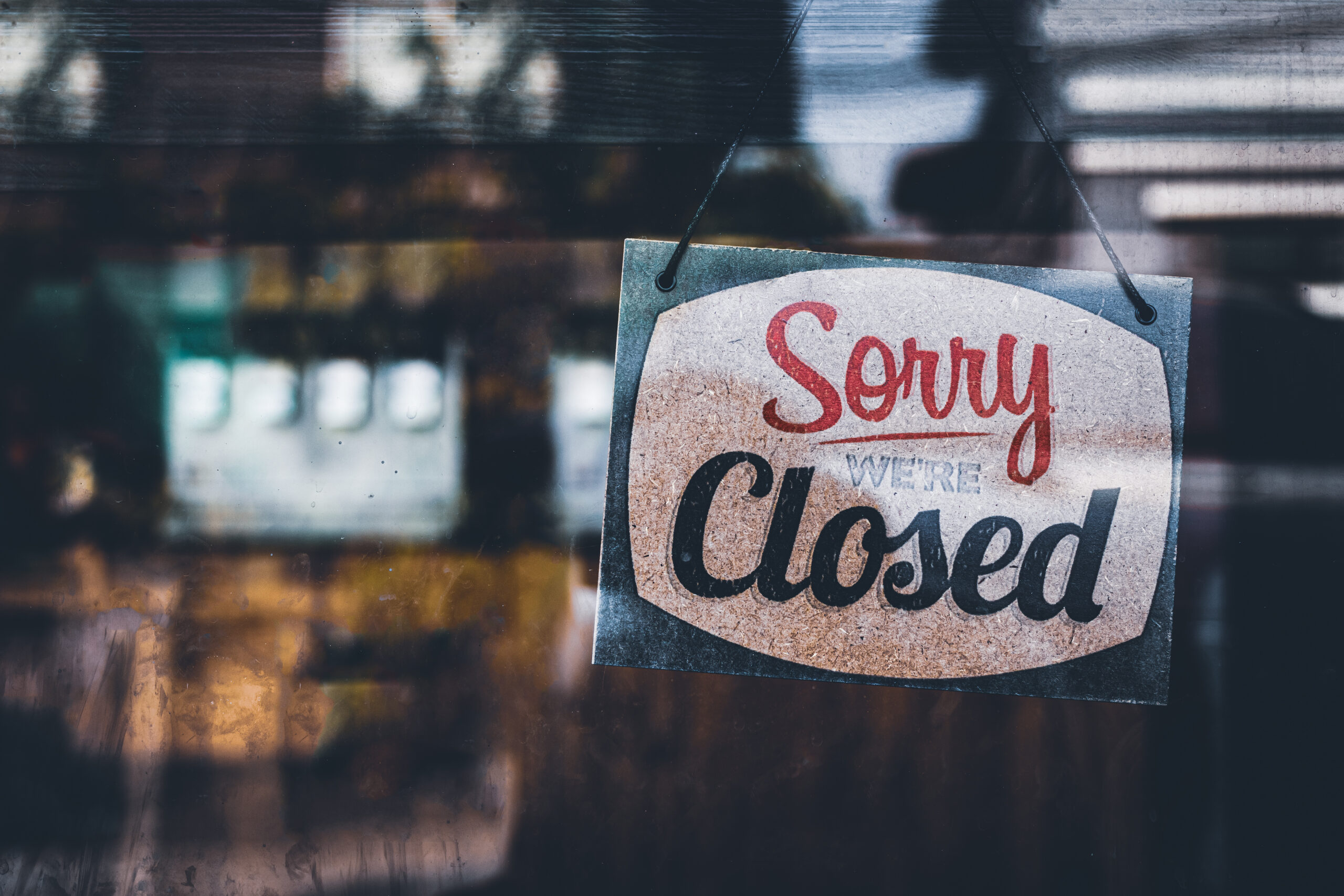 small business with "sorry, we're closed" sign hanging in the window