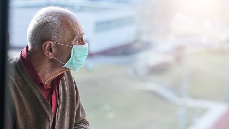 medical care, aged pensioner man with gray hair wearing medical facemask looking through window health care concept
