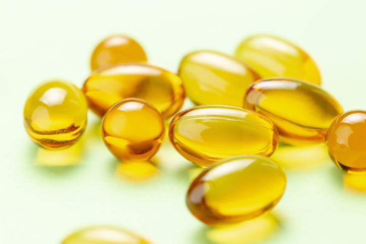 Close up of Vitamin D Omega 3 fish oil capsules on green background