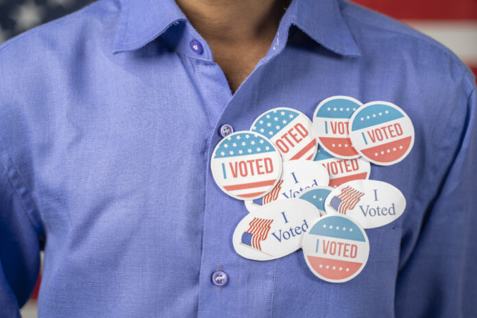 Close up of multiple I Voted stickers on blue shirt - Concept of US election voter fraud by placing multiple voting stickers.