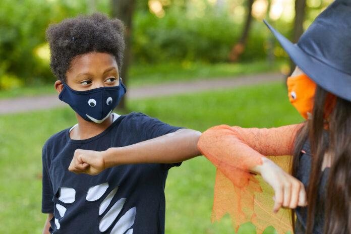 African boy in costume playing with his friend in the park outdoors