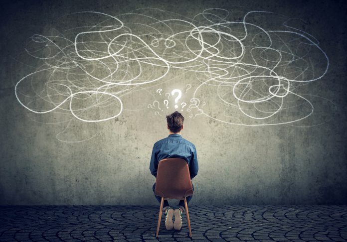 Back view of a thoughtful young businessman sitting on chair looking at a scribble on a wall feeling confused with too many questions School choice