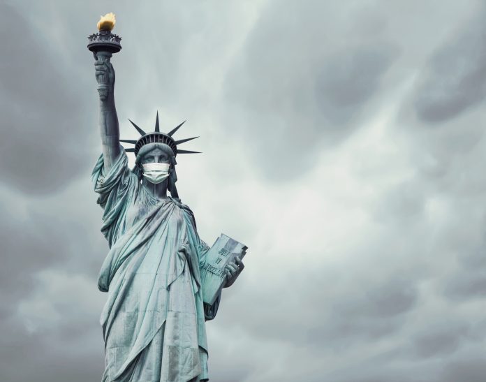 Stock photo of the New York's Statue of Liberty with a mask on its face caused by the coronavirus covid-19 and copy space on the right