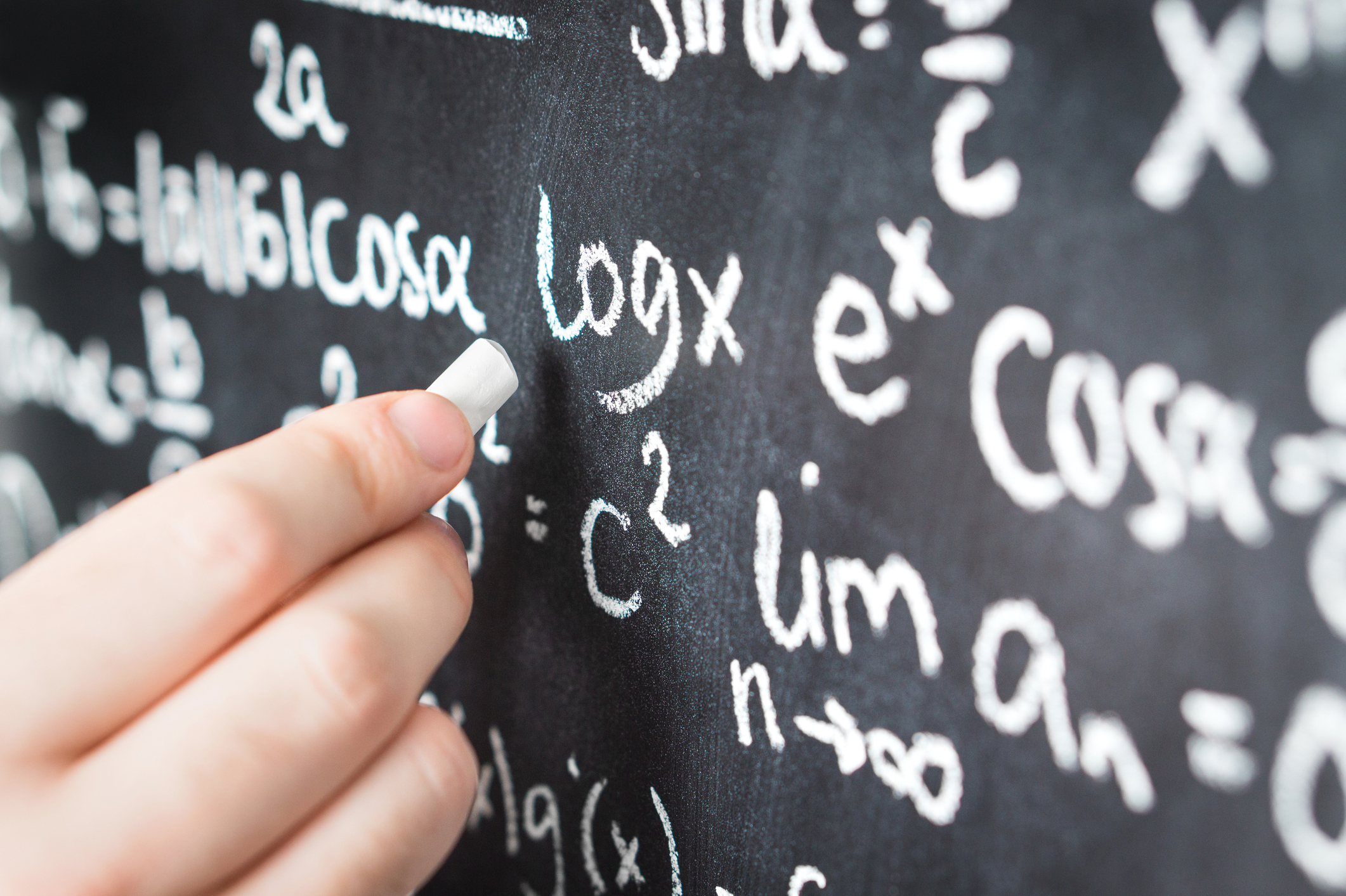 Professor writing mathematical formula and equation to blackboard in school classroom. College or university teacher or student with chalkboard. Science, education and math concept.