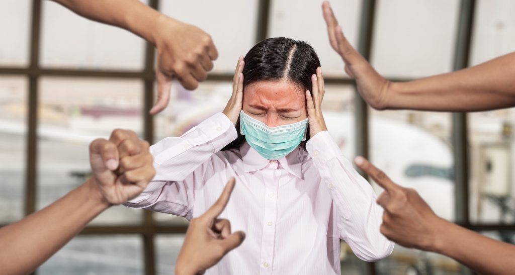 Asian woman was sick with high fever wearing hygienic mask are bullied and hate surrounded by hands mocking her, scoffing in the outbreak situation of Coronavirus 2019 infection or Covid-19