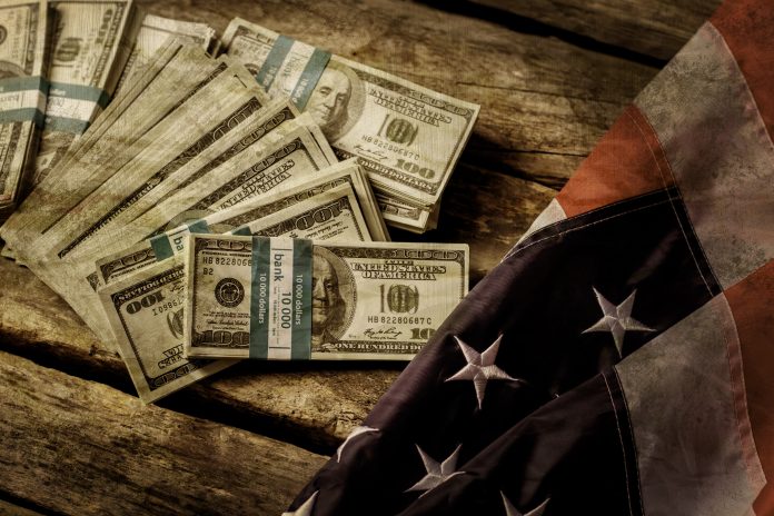 Old USA flag and dollars. Cash laying beside aged flag. Good old times. Nation used to be richer.