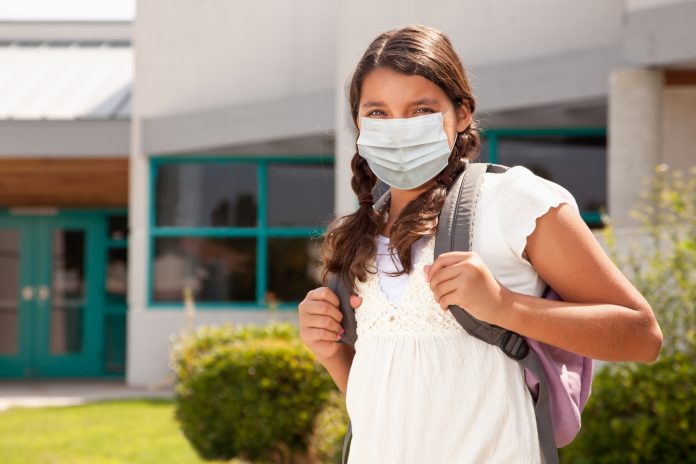 Hispanic Student Girl Wearing Face Mask with Backpack on School Campus.