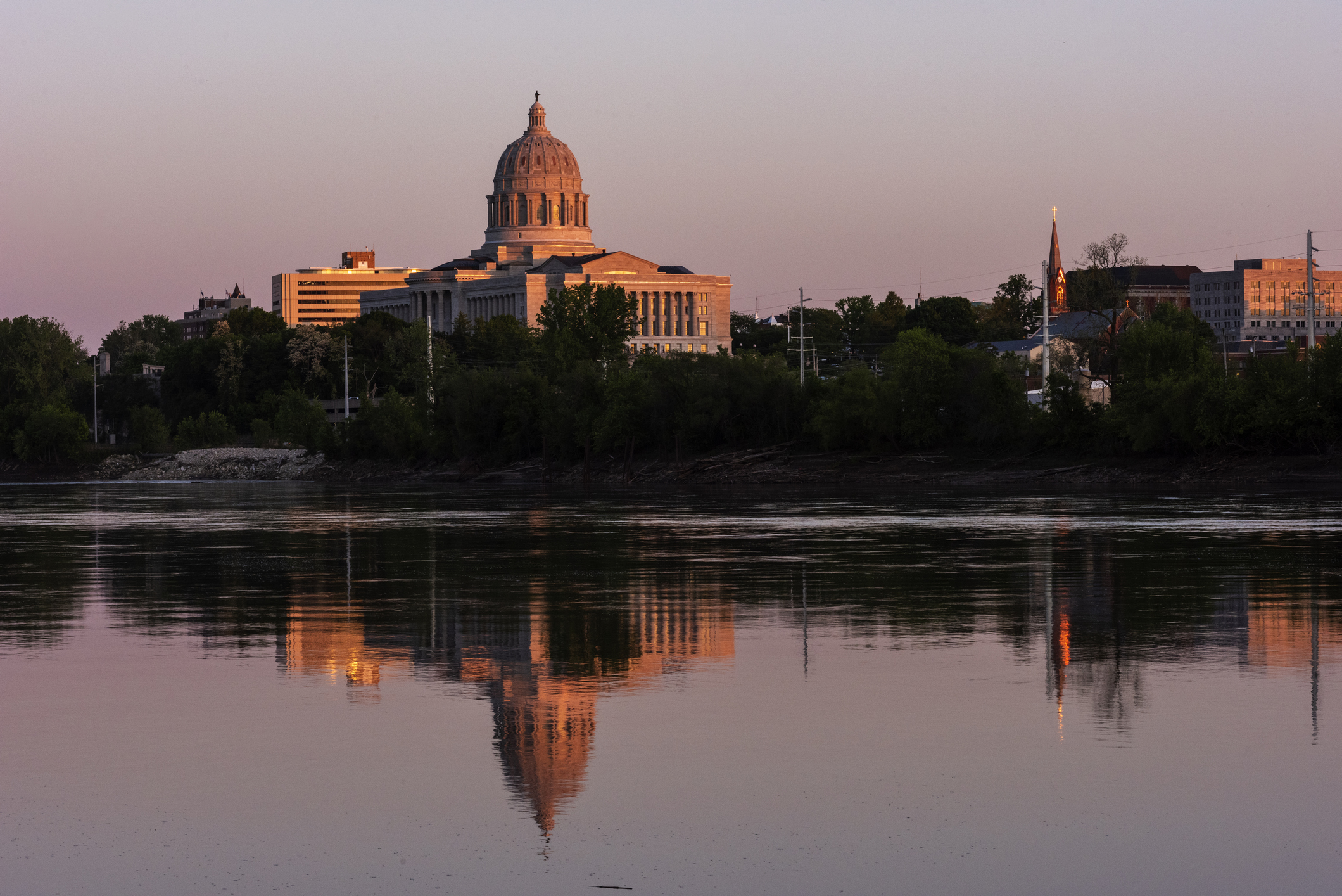 The Missouri State Capitol in Jefferson City is reflected in the Missouri River at sunset on May 13, 2021.