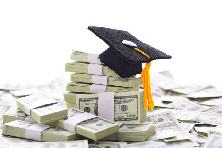 Mortarboard on a pile of money representing the steep increase of college tuition